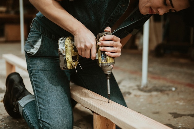 Female carpenter drilling a lumber