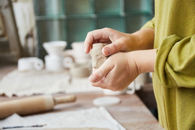 Photo female ceramist working in pottery studio. ceramist's hands dirty of clay. process of creating pottery. master ceramist works in her studio