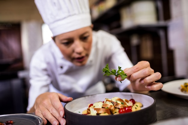 Female chef garnishing delicious desserts in a plate