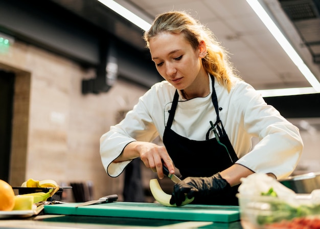 Female chef with glove slicing banana