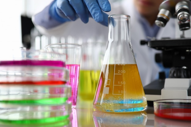 Female chemist in blue protective gloves hand hold test tube