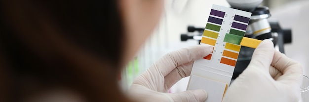 Female chemist holding litmus paper in hands