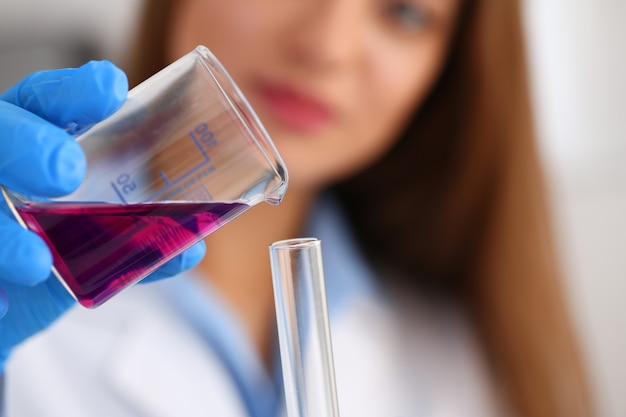 Female chemist holds test tube of glass in his hand overflows a liquid