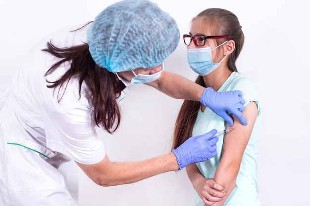 Female childrens doctor or nurse giving shot or vaccine to patients shoulder  young girl vaccination...