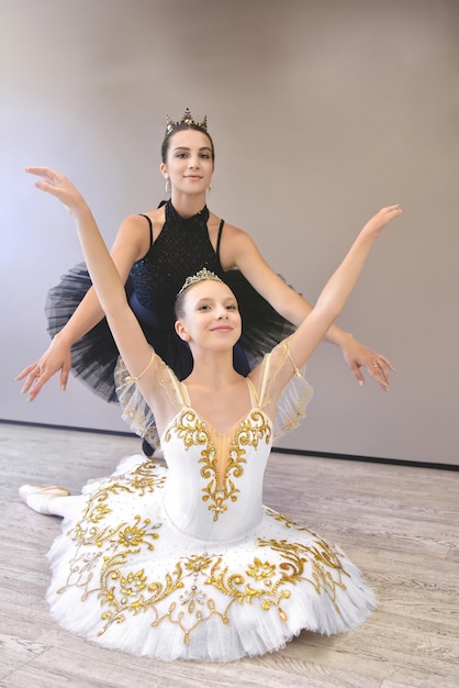 Female choreographer teacher mentor trainer of classical dance teaches posture help with stretching to young student learn dancing teen girl ballerina