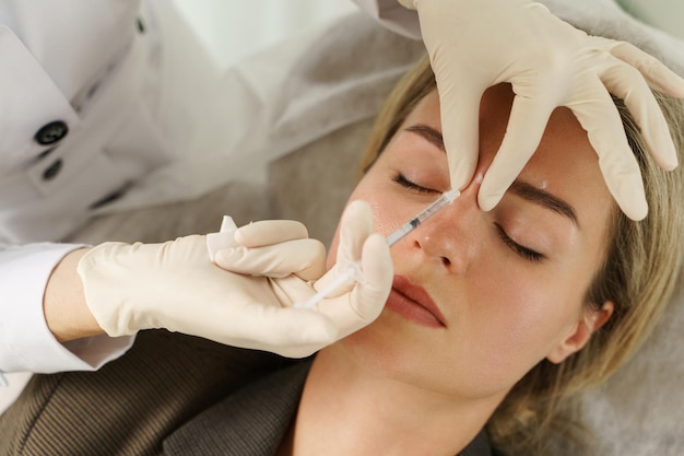 Female client during facial filler injections in aesthetic medical clinic