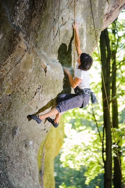 Female climber climbing with rope on a rocky wall