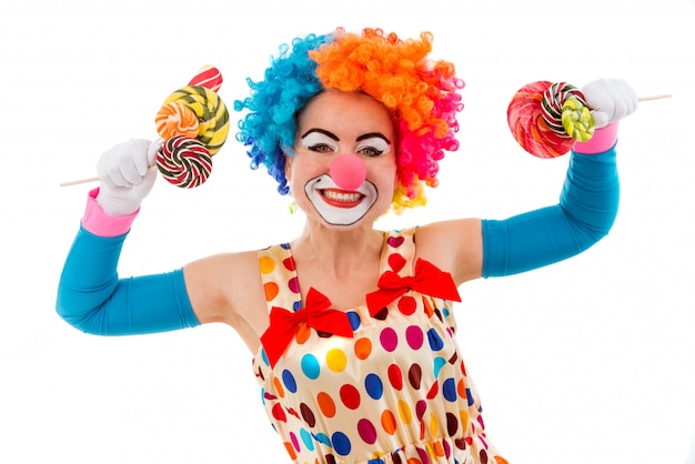 Female clown in colorful wig holding lollipops in both hands