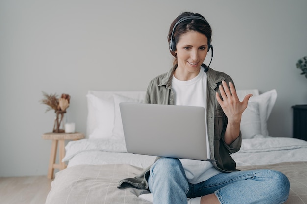 Female coach in headset conducts online consultation webinar by video call on laptop at home