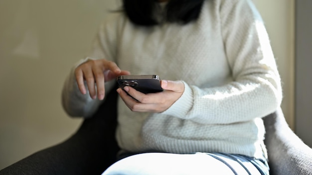 A female in the coffee shop using her smartphone closeup and cropped shot