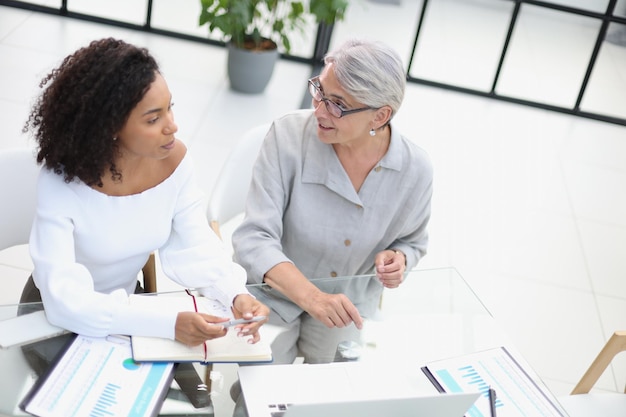 Female colleagues met in the office hall discussing work issues