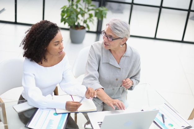 Female colleagues met in the office hall discussing work issues