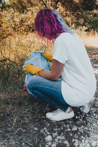 Female collecting the trash and putting in a plastic garbage bag - environmental pollution concept