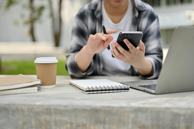 A female college student using her smartphone while sitting at a campus park