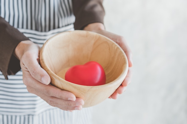 female cook holds a cup with a heart in it.Serve with love and caring concept.