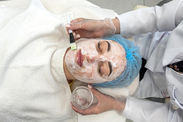 Female cosmetologist in protective gloves works with a client in her salon