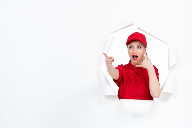 Female courier in red uniform pointing at something on white