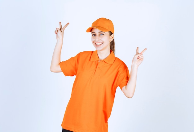 Female courier wearing orange uniform and cap showing peace sign.