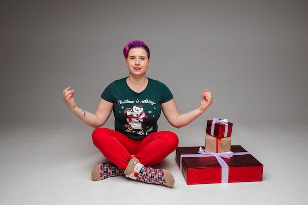 Female crossing her legs and raising the arms with fingers touching each other next to the gift packs. Happy holidays concept