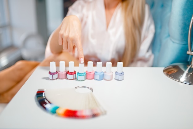 Female customer choosing nail varnish in beauty shop.