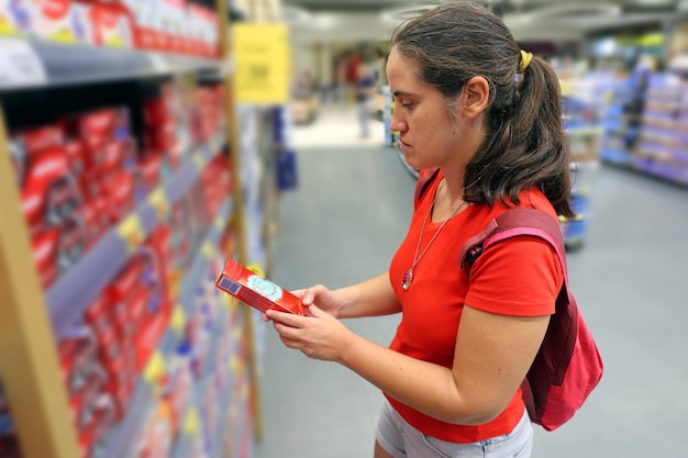 A female customer is interested in the content of canned tuna fish in grocery store supermarket