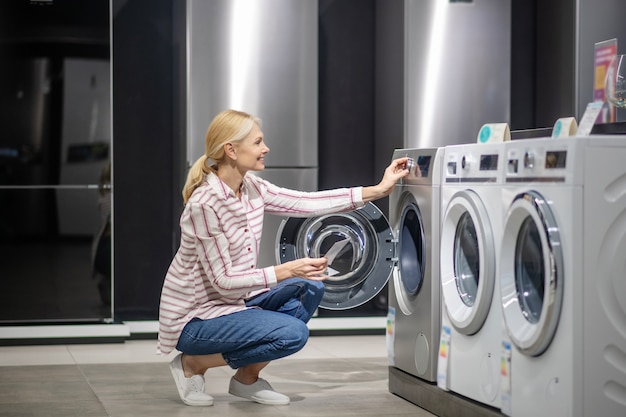 Female customer in striped shirt choosing a washing machine in megastore