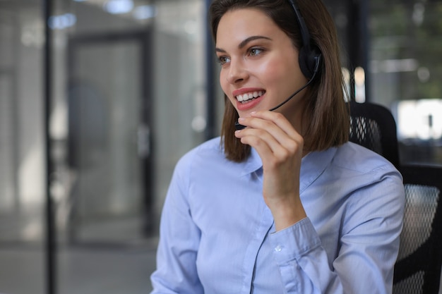 Female customer support operator with headset and smiling.