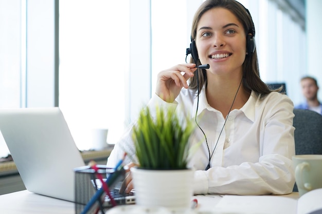 Female customer support operator with headset and smiling.