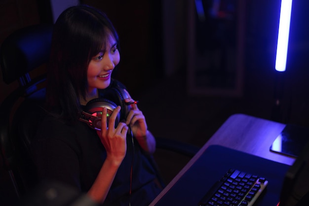 Female cyber hacker gamer in headphone around neck watching video games on monitor with having fun