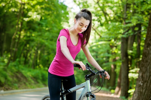 Female cyclist on a bike on asphalt road in the forest