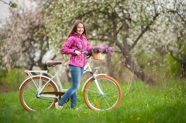 Female cyclist with vintage white bicycle in spring garden