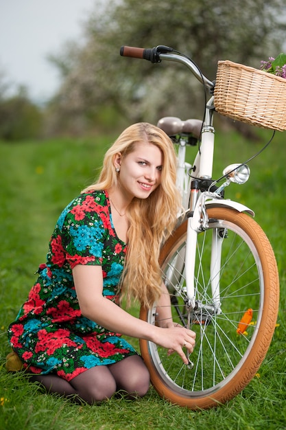 Female cyclist with vintage white bicycle in spring garden