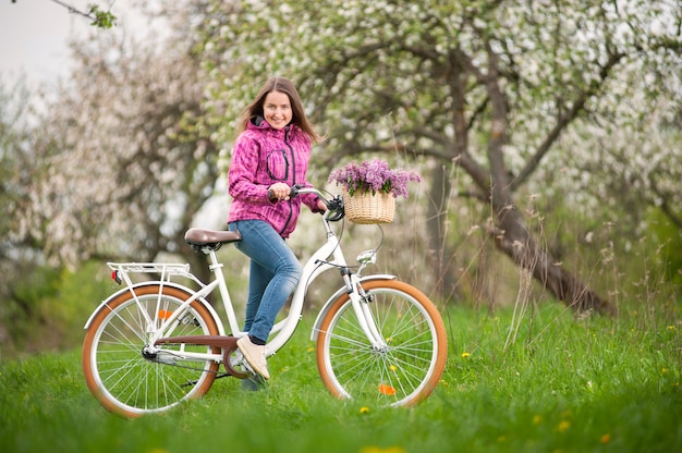 Female cyclist with vintage white bicycle in spring garden