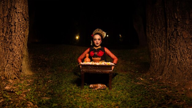 Photo a female dancer looks focused on her ritual with a peaceful facial expression in front of offerings