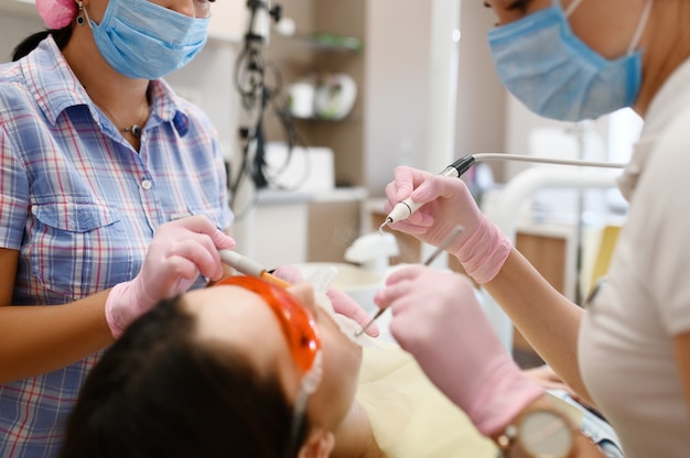 Female dentist and assistant are treats patient in clinic, stomatology