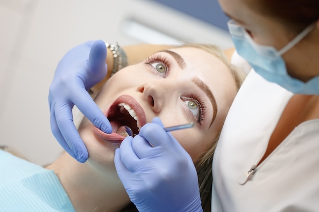 Female dentist checking patient girl teeth