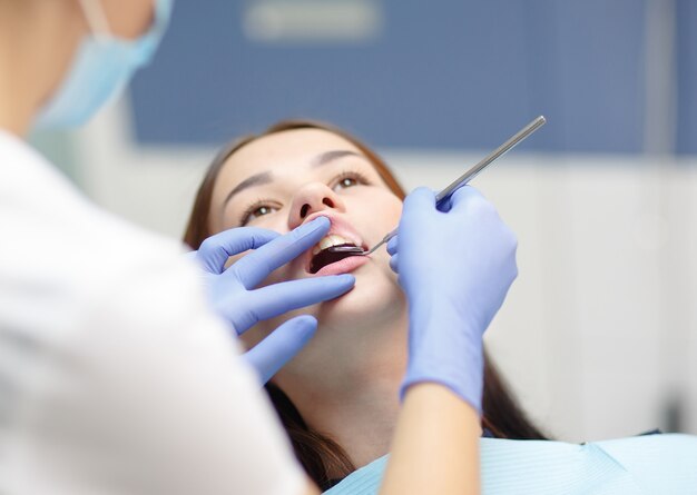 Female dentist checking patient girl teeth