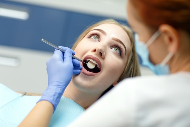 Female dentist checking patient woman teeth