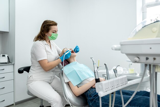 Female dentist treats the teeth of a young girl patient lying in the clinic dentistry healthy oral cavity teeth smile