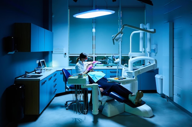 Female Dentist very carefully check up and repair tooth of his young female patient Happy young woman sitting in dental chair at dentist office