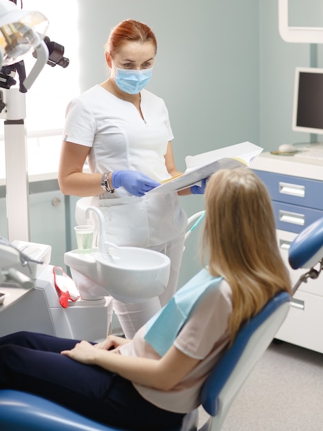 Female dentist with patient woman talking at dental clinic office