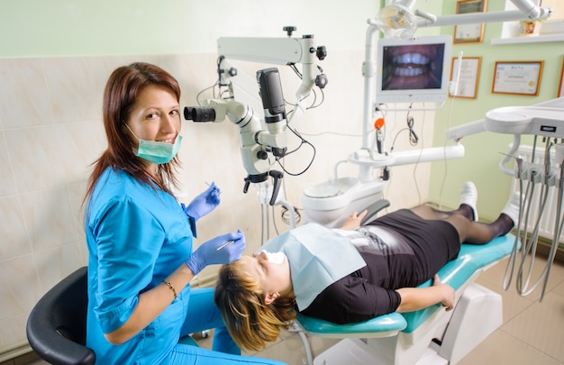 Female dentist working with microscope at modern dentist clinic