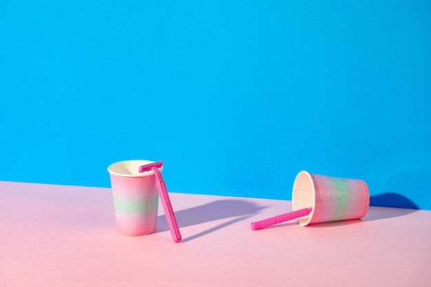 Female disposable razor in a cup, studio shot, copy space