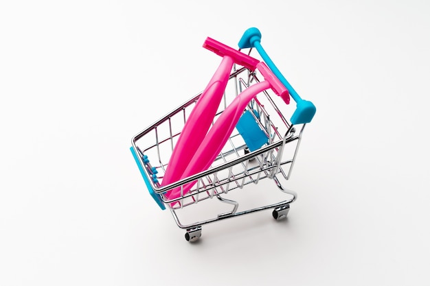 Female disposable shaver in toy shopping cart on white background close up