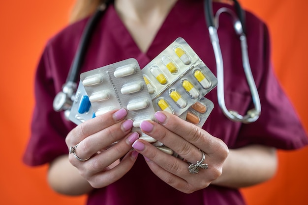 Female doctor in clothes stands and holds pills in hands isolated on plain background