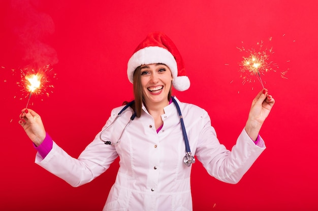 A female doctor congratulates patients on the new year Doctor with sparklers on a red background