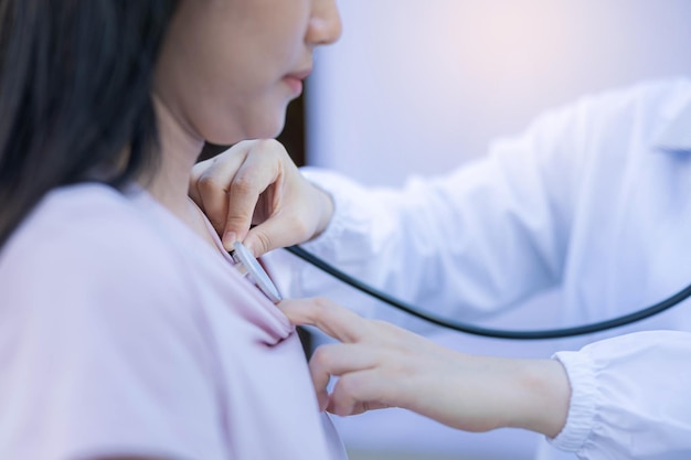 Female doctor examines woman with stethoscope to coronavirus pneumonia signs checking chest of woman at field hospital.