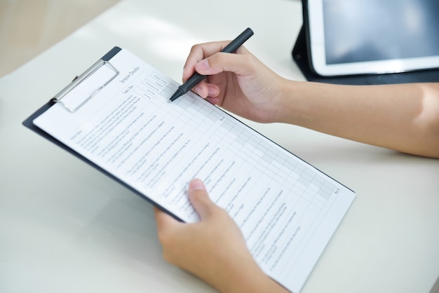 Female Doctor hands taking note on checklist.