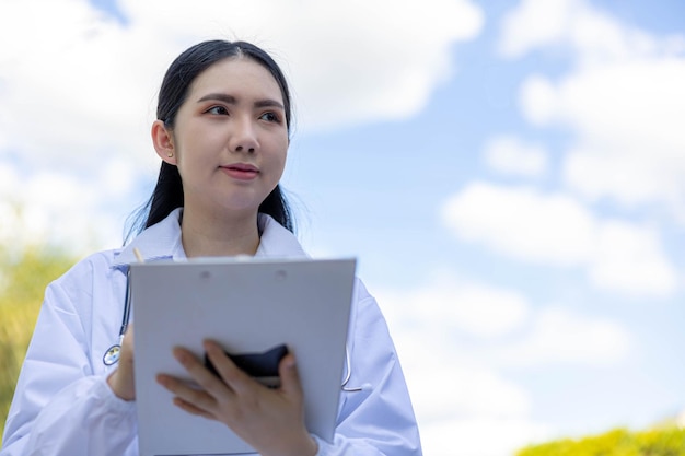 A female doctor holding clipboard working on the field with sky backgroundx9