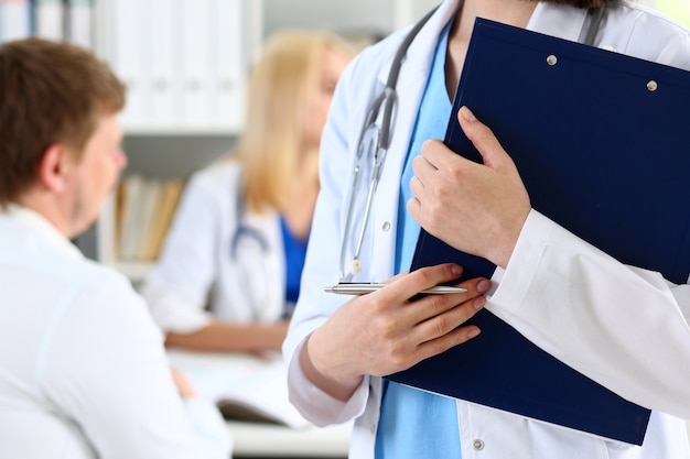 Female doctor holding silver pen and clipboard